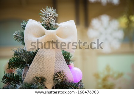 White bow on the top of Christmas tree