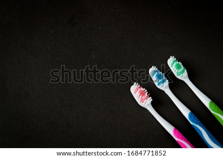 three toothbrushes of blue, green and pink colors on a black background, close-up