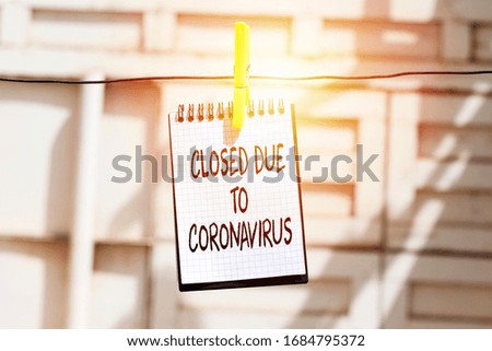 hangs notebook with information about the store closing on a shop window due to the coronavirus