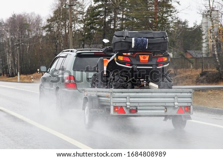 Quad bike transportation, a 4x4 car with a trailer on the suburban Highway Royalty-Free Stock Photo #1684808989