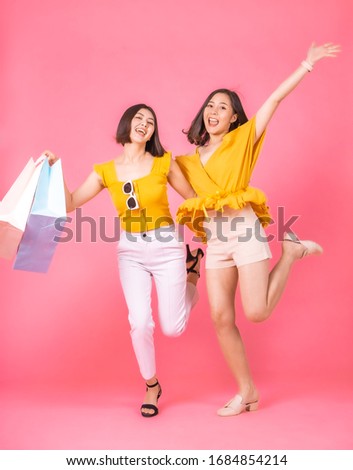 Asian pretty young woman sitting on pink  pastel background. She smiling and  happy shopping bags. she nice-looking lovely attractive shine.Friend  jumping happy to shopping time.