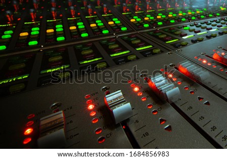 Some moving faders in a mixing console in a sound studio