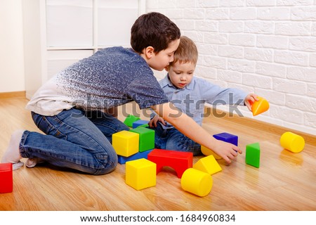 Beautiful children playing with constructor on floor at home