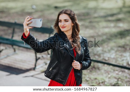 A cute young woman takes a selfie in the park. There is spring weather. The day is clear.