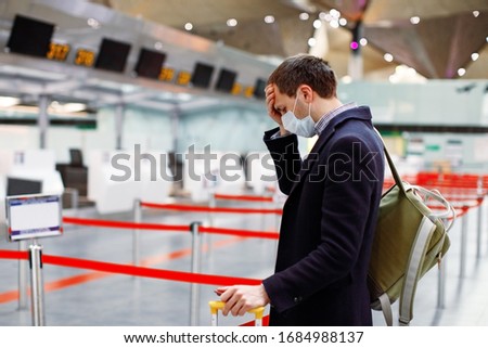 Man in mask at empty airport at check in in coronavirus quarantine isolation, waiting for departure, tourism industry crisis, pandemic infection spread, travel restrictions and border shutdown Royalty-Free Stock Photo #1684988137