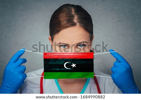 Coronavirus in Libya Female Doctor Portrait hold protect Face surgical medical mask with Libya National Flag. Illness, Virus Covid-19 in Libya, concept photo