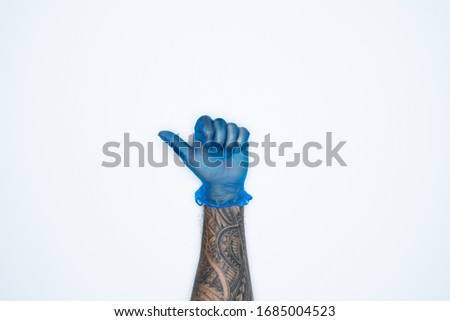 A man hand and gestures in Blue rubber glove shows thumb up sign isolated on white background.