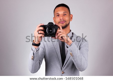 African american photographer holding a dslr camera, over gray background - Black people