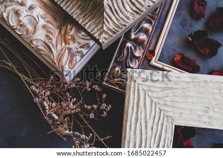 Details of empty picture frames and dried flowers on black backdrop. Framing workshop concept.
