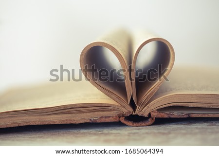 Books pages of old book are twisted as hear sign. Small depth of focus Royalty-Free Stock Photo #1685064394