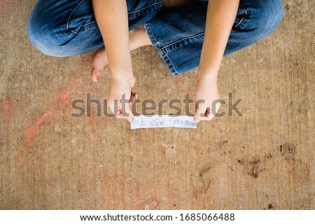 child sitting criss cross holds handwritten mothers day love note