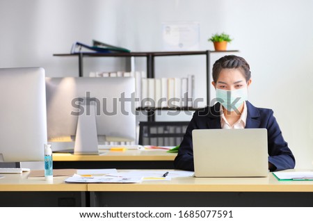 Female employee wearing medical facial mask working alone as of social distancing policy in the business office during new normal change after coronavirus or post covid-19 outbreak pandemic situation Royalty-Free Stock Photo #1685077591