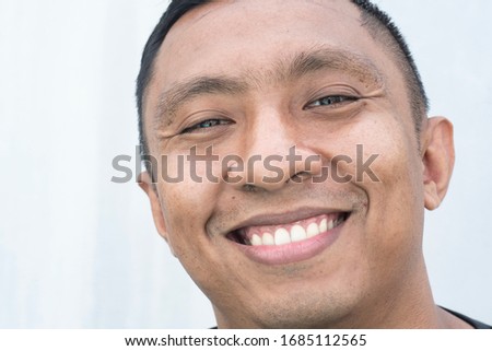A closeup portrait of a face of an Asian Indonesian male model who smiles with his mouth wide open. he looks happy. Picture is on white background Royalty-Free Stock Photo #1685112565