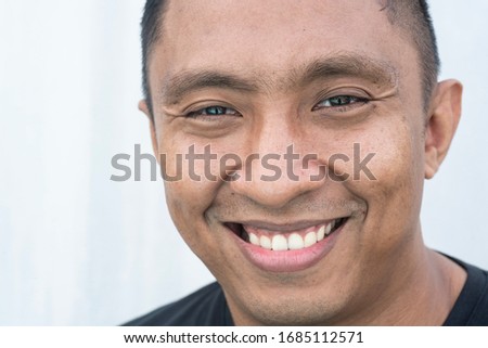 A closeup portrait of a face of an Asian Indonesian male model who smiles with his mouth wide open. he looks happy. Picture is on white background Royalty-Free Stock Photo #1685112571
