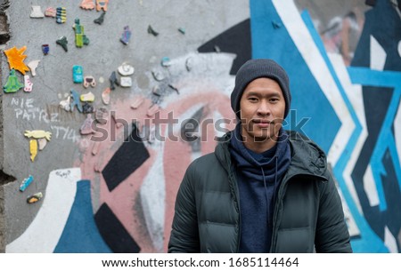 A portrait of an Asian Thai man wearing a winter jacket and a beanie hat in Krakow Poland Royalty-Free Stock Photo #1685114464