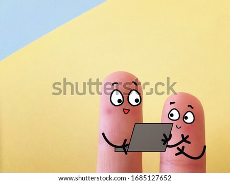 Two fingers are decorated as two person. One of them is teaching another how to use laptop.