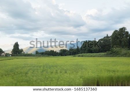 Great landscape view from the paddy fields of mountain range and ski pistes through the sky, the forests and the clouds in Japan.