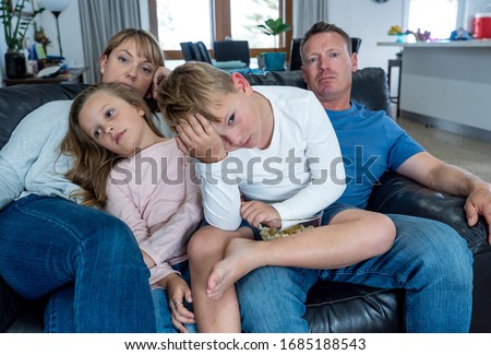 Coronavirus lockdow. Bored family watching tv helpless in isolation at home during quarantine COVID 19 Outbreak. Mandatory lockdowns and self isolation recommendations forces families stay home. Royalty-Free Stock Photo #1685188543