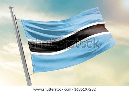 Botswana national flag cloth fabric waving on the sky with beautiful sun light - Image
