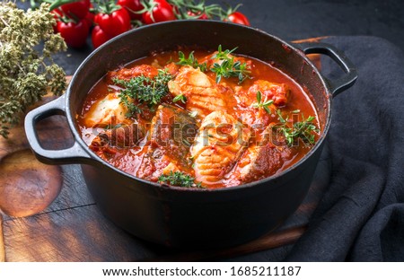 Traditional Brazilian fish stew moqueca baiana with fish filet in tomato sauce as closeup in a modern design cast-iron roasting dish  Royalty-Free Stock Photo #1685211187