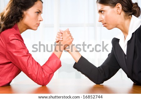 Profile of two women in struggle while their arms being wrestled