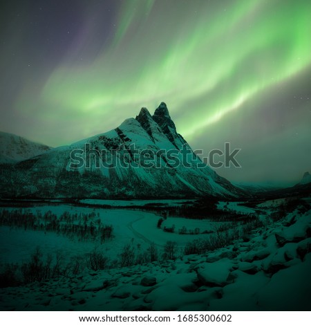 Otertinden peak in Norway, under the northern lights
Beautiful mountains through Arctic Norway, with the Auroras dancing on top.  Lyngen Alps Scandinavia.
Mountain which is covered with snow. 