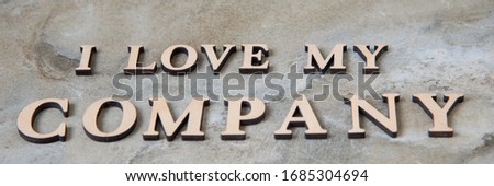 i love my company , writen wooden letters on stone background. Concep image.