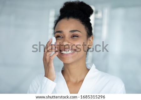 Headshot portrait African ethnicity young woman cleanses face holding super gentle facial sponge ideal for daily exfoliation. Skincare, self-care, helpful modern tool usage for skin perfection concept Royalty-Free Stock Photo #1685315296