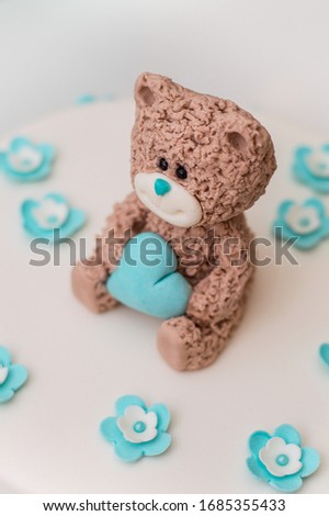 Beautiful blue children's cake covered with sugar mastic with a teddy bear figure