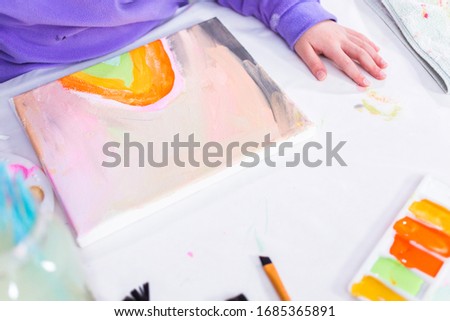 Little girl painting on canvas with arcylic paint.