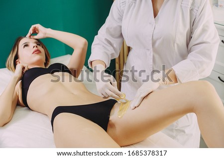 Depilation Of The Intimate Bikini Zone With Sugar Paste. The master does depilation of the bikini zone to a beautiful girl in a black swimsuit