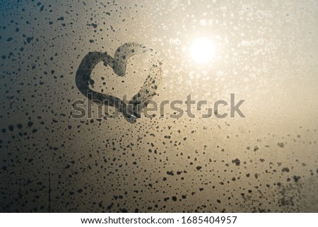 Close up of love heart drawn on natural fogged glass background. Window drops emotional shaped gesture