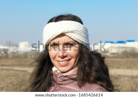 A girl walks through the spring park. Posing standing in a meadow. The city is visible on the horizon. Close-up shot.