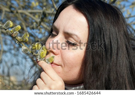 A girl walks through the spring park. Examines a flowering willow.