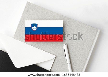 Slovenia flag on minimalist letter background. National invitation envelope with white pen and notebook. Communication concept.