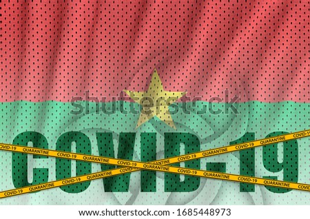 Burkina Faso flag and Covid-19 inscription with orange quarantine border tape. Coronavirus or 2019-nCov virus concept