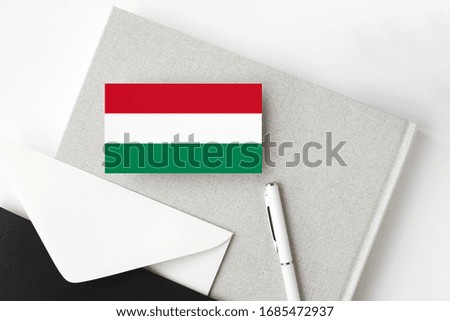 Hungary flag on minimalist letter background. National invitation envelope with white pen and notebook. Communication concept.