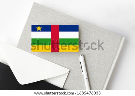 Central African Republic flag on minimalist letter background. National invitation envelope with white pen and notebook. Communication concept.