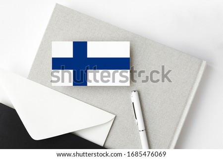 Finland flag on minimalist letter background. National invitation envelope with white pen and notebook. Communication concept.