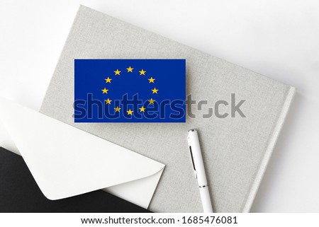 European Union flag on minimalist letter background. National invitation envelope with white pen and notebook. Communication concept.