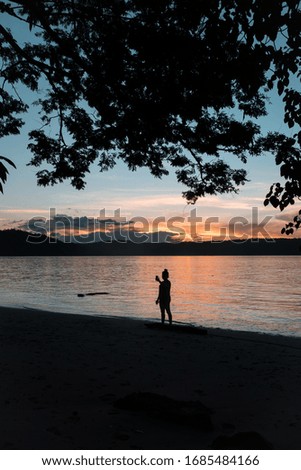 Woman taking a photo at sunset on the beach at sunrise on one of the beaches of the Papagayo Peninsula in Costa Rica. South America.