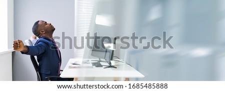 African Man Doing Stretching Exercise At Office Desk Royalty-Free Stock Photo #1685485888
