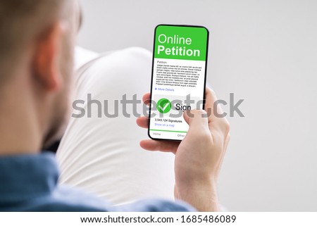 Man Looking At Online Petition Form On Smartphone Royalty-Free Stock Photo #1685486089