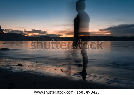 Woman walking along the blurred beach with sunrise in the background on one of the Costa Rican beaches on the Papagayo Peninsula. South America.