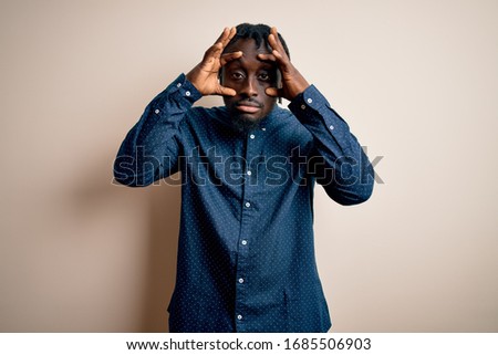 Young handsome african american man wearing casual shirt standing over white background Trying to open eyes with fingers, sleepy and tired for morning fatigue