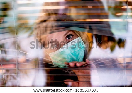 Worried Woman looking through window from home in quarantine during Corona virus.Anxiety Woman in self distancing isolation due to Covid-19.Stay at home in time of pandemic concept 