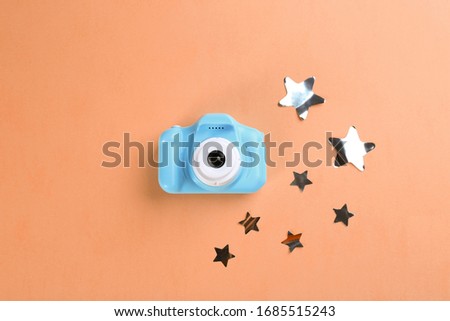 Toy camera and stars on orange background, flat lay