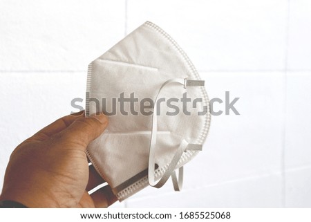 Holding a doctor's mask on the white plaster floor                               