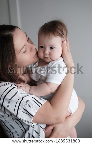 Smiling mother holding her newborn baby daughter at home
