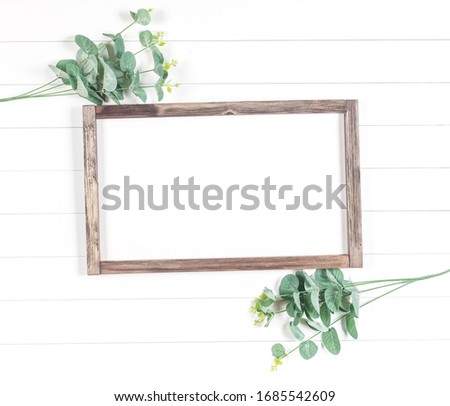 frame of rough wood on a light background with eucalyptus branches - add your design